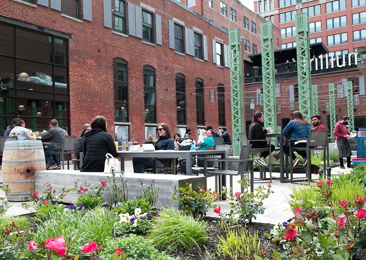 Guests dining on the patio at Trillium Fort Point, with flowers in the foreground