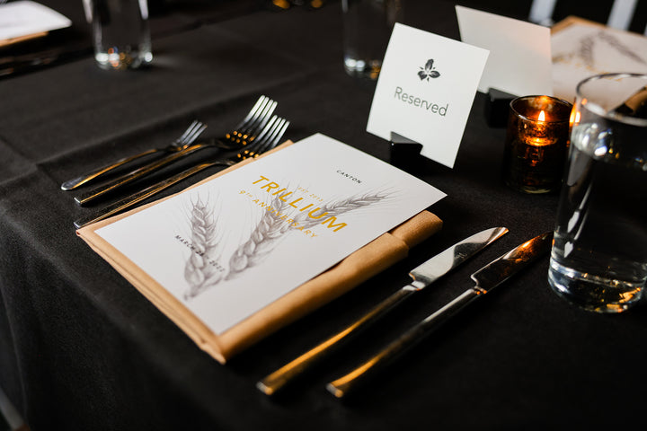 Trillium event table setting with menu, silverware, and reserved sign