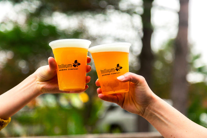 Close up of two hands cheersing with Trillium beers